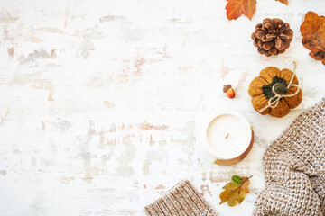 Cozy autumn background on white. Warm sweater, autumn leaves, candle and decor. Flat lay image with copy space.