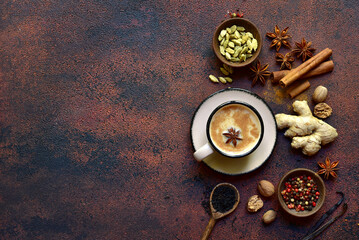 Cup of masala tea with ingredients for making on a dark slate, stone or concrete background . Top view with copy space.
