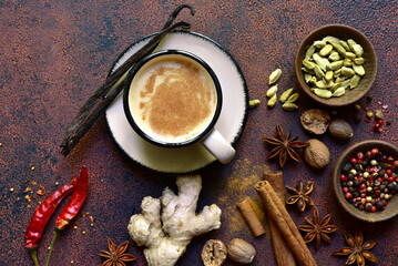 Cup of masala tea with ingredients for making on a dark slate, stone or concrete background . Top...