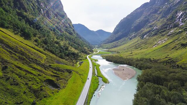 Cars driving on the mountain road in a great big Valley in Norway. Beautiful nature landscape. Rivers and mountains. 