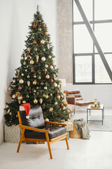 Cozy Armchair near Christmas tree in sunny room with big windows. Santa's hat in the morning. Nobody. copy space. Greeting postcard 