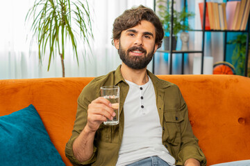 Thirsty man hold glass of natural filtered aqua make sips drinking still water preventing...