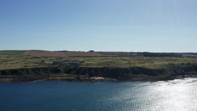 Drone shot of the coastline in Scotland, clear blue skies and vast country side