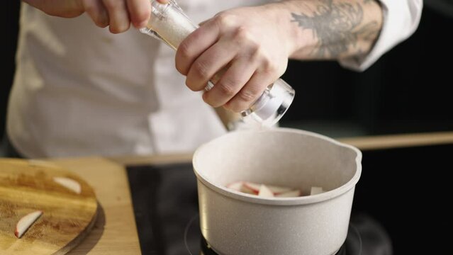Macro shot of a chef salting on apple using salt mill in slow-motion. Chef milling the salt, using kitchen stuff