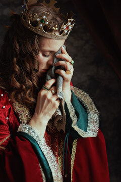 unhappy medieval queen in red dress with handkerchief crying
