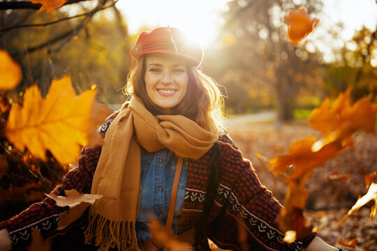 Portrait of happy elegant female throwing autumn leafs