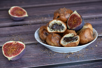 Delicious homemade profiteroles cakes with cocoa cream filling and chocolate chips. Choux pastry, halved cream puffs, fig halves. Dark wooden table, rustic background. 