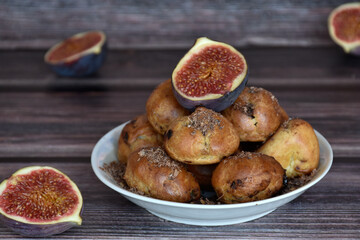 Delicious homemade profiteroles cakes with cocoa cream filling and chocolate chips. Choux pastry, cream puffs on plate, fig halves, wooden table background. 