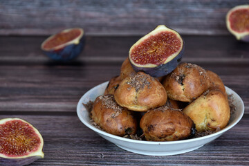 Delicious homemade profiteroles cakes with cocoa cream filling and chocolate chips. Choux pastry, cream puffs on plate, fig halves, wooden table background. 