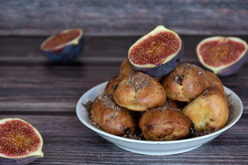 Delicious homemade profiteroles cakes with cocoa cream filling and chocolate chips. Choux pastry, cream puffs on plate, fig halves, wooden table background. 