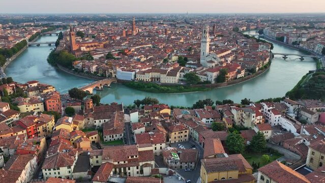 Establishing Aerial View Shot of Verona historical city centre, Ponte Pietra bridge across Adige river, Verona Cathedral, Duomo di Verona, red tiled roofs, Veneto Region, Italy, track in