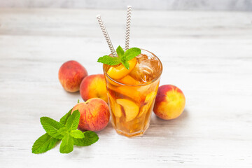 Peach ice tea in a glass with mint on white wooden table. Top view. 
