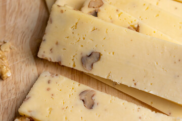 Sliced piece of milk cheese with walnuts