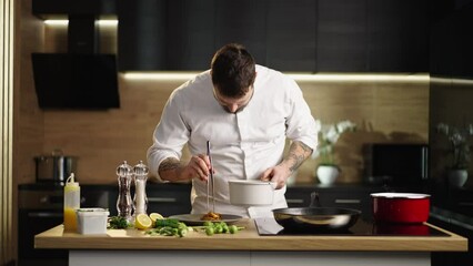 Young bearded chef putting a red prawns on the top of pasta into the plate. Slow-motion shot