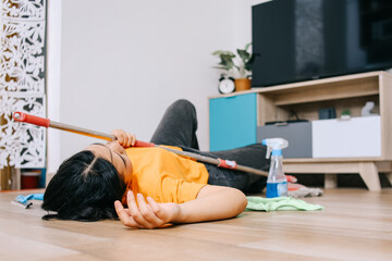 Tired young Asian woman lying on floor after cleaning the house