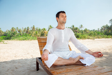 Fototapeta na wymiar Young Adult Man Meditating on Sunny Tropical Beach