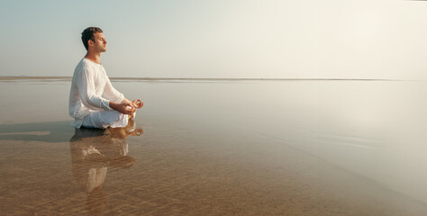 Young Adult Man Meditating on Sunny Tropical Beach