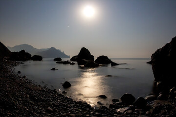 Fototapeta na wymiar The full moon shines space on the stone seashore. landscape in nature