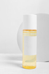 Bottle of cosmetic product on white wooden table