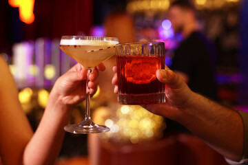 People clinking glasses with fresh cocktails in bar, closeup