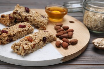 Tasty granola bars and ingredients on grey wooden table
