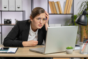 Caucasian business woman programmer software developer fingers crossed working on laptop loses becoming surprised by bad news results fortune loss fail at office. Deadline, bankruptcy. Freelancer girl