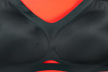 central part of a black bra on red background - obrazy, fototapety, plakaty