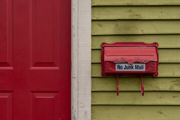 A postal mailbox or letterbox made of red metal with a decorative flower and leaf pattern on the...