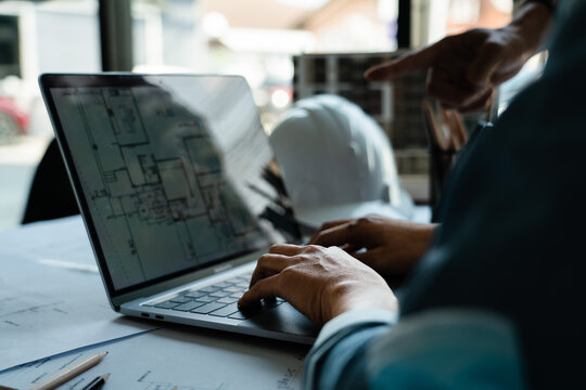 Two engineer working to discuss and brainstorming about construction blueprint on laptop in office