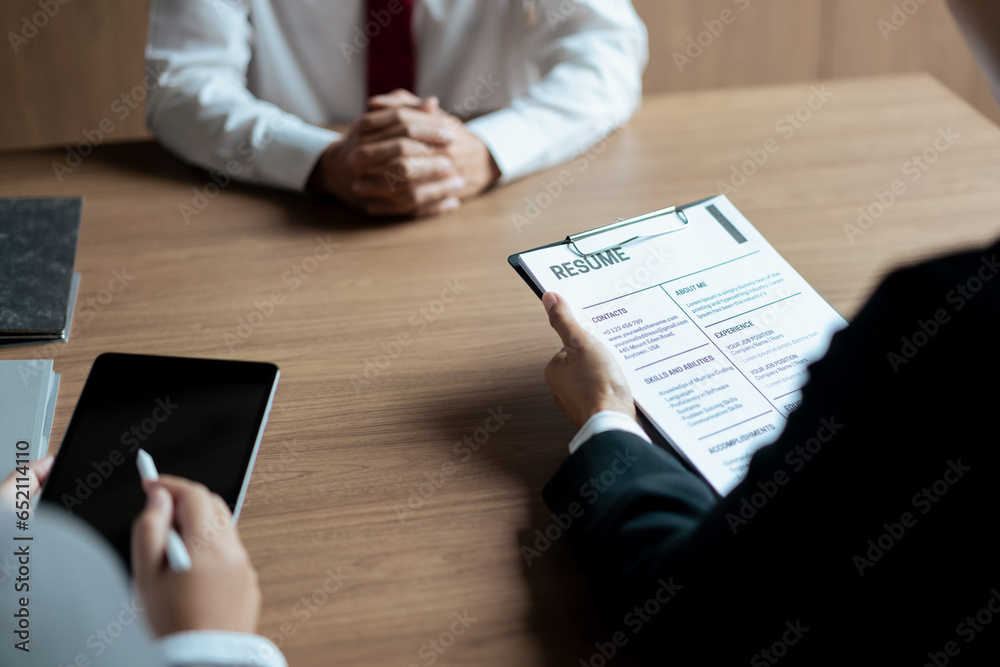 Wall mural hr manager woman reading resume and writing data on tablet during job interview with male candidate