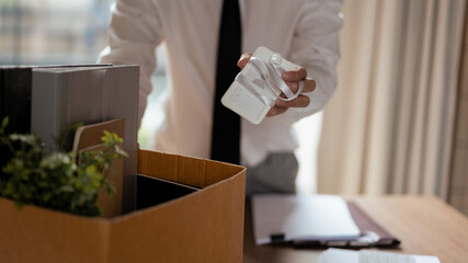 Male employee packing belongings and employee card in cardboard box after sends resignation letter