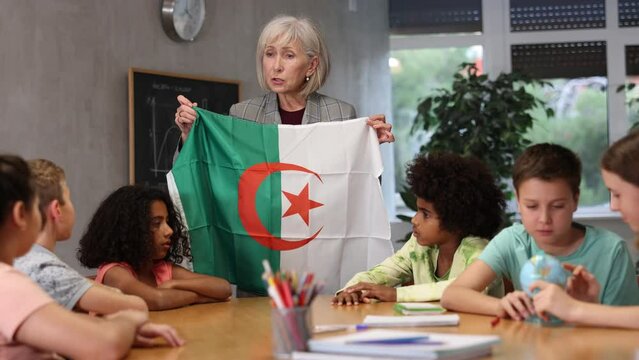 Kids learning together about algeria in geography class Female teacher showing algerian flag to kids in geography . High quality 4k footage
