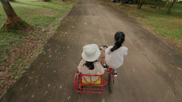 Young girl and her sister riding the tricycle with cargo bike together