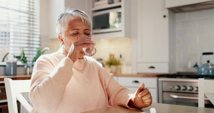Old woman with pills in kitchen, health and drinking water, supplements for wellness or sick with daily routine at home. Retirement, treatment with medicine and healthcare, drugs and vitamins