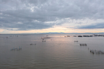 Aerial view of fishing trap net in canel with fisherman urban city village town houses, lake or river. Nature landscape fisheries and fishing tools at Pak Pha, Songkhla, Thailand. Aquaculture farming