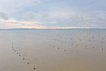 Aerial view of fishing trap net in canel with fisherman urban city village town houses, lake or river. Nature landscape fisheries and fishing tools at Pak Pha, Songkhla, Thailand. Aquaculture farming