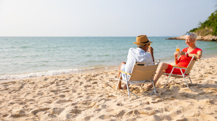 Celebrate Elderly couple man and woman celebration and drinking and looking at the sea sky sitting on chair on beach. Vacation trip summer holiday. Party, Holiday, Summer, Friendship