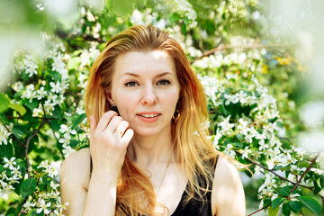 woman portrait on flower apple tree. white caucasian female with long yellow red hair. summer