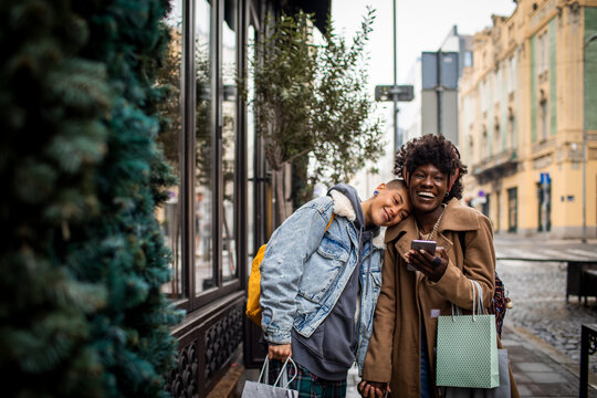 Young interracial lesbian couple shopping and using a phone in the city