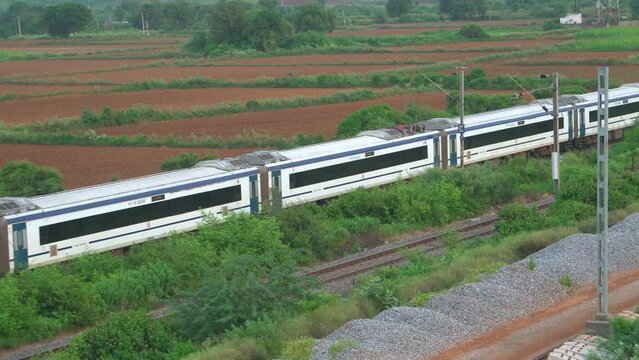 Pan close shot of Vande Bharat Express train moving fast on a Railway track of Gwalior India