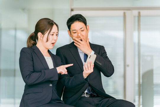 スマホ・スマートフォンを見てショック・驚く会社員（炎上・トラブル・失敗・カスハラ・困る）
