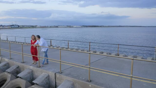 Red Dress Romance: Couple's Tranquil Talk on Galway's Causeway