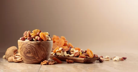 Tuinposter Dried fruits and nuts on a beige ceramic table. © Igor Normann