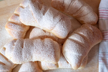 Freshly baked sweet rolls with powdered sugar on a wooden board