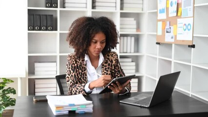 Asian Business woman using tablet and laptop for doing math finance on an office desk, tax, report, accounting, statistics, and analytical research concept in office..
