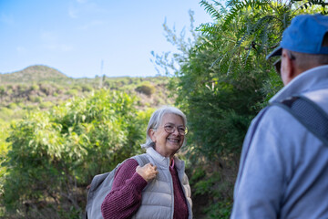 Happy caucasian senior couple in outdoors excursion in mountain foothpath enjoying freedom in nature. Active and healthy lifestyle in retirement