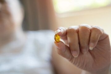 Cropped image of older woman holding a pill or vitamin and ready to take it for her good healthy.