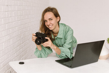 Smiling young woman with camera and a laptop. Photo processing. Natural. Woman photographer