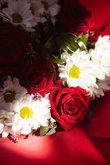 A bouquet of red roses and white daisies in a red wrapper