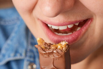 Close up of the open mouth of a happy Caucasian woman and a bitten chocolate bar. Front view. High angle view.